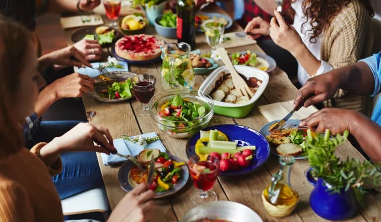 Friends gathered around a wooden table sharing food